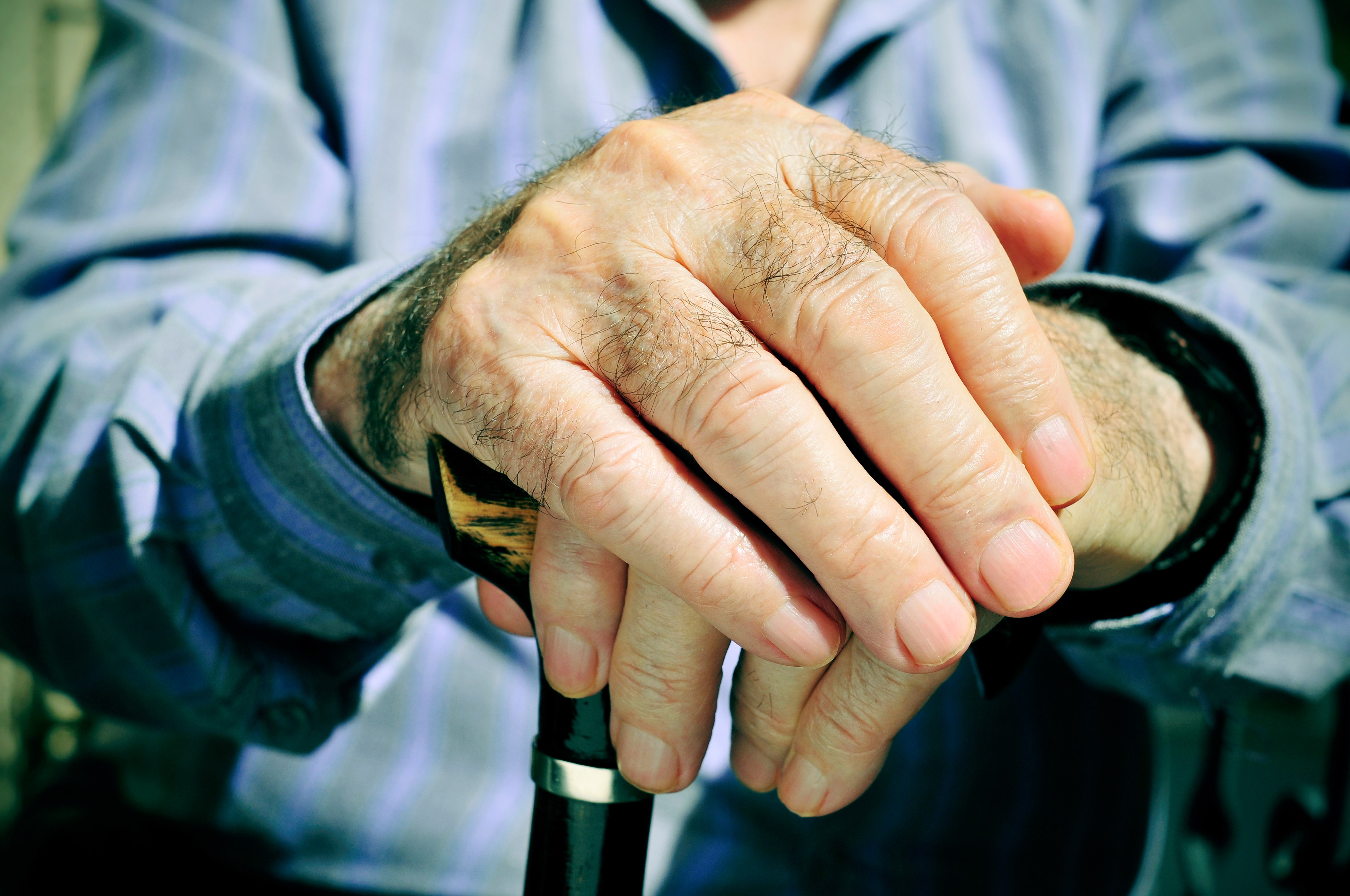 Ældre person med hænder på en stok